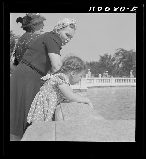 Detroit, Michigan. Woman and child watching fish in a pond