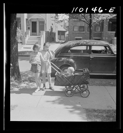 Detroit, Michigan. Little girls wheeling baby brother in a carriage