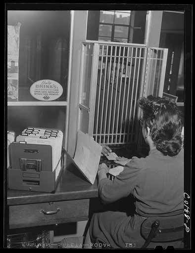 Cashier receiving rent from Joseph Griswold, who has a three-room apartment at the Ida B. Wells Housing Project, Chicago, Illinois. This rent is twenty dollars a month