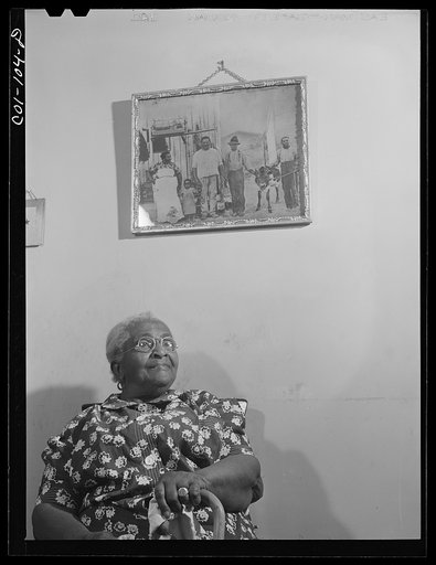 Portrait of Mrs. Ella Patterson, the oldest resident at the Ida B. Wells Housing Project, Chicago, Illinois. She is 102 years old. On the wall is an old picture of her family taken about fifty-five years ago