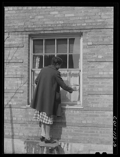 Mrs. Josephine Edwards washing the windows at her apartment. Ida B. Wells Housing Project, Chicago, Illinois