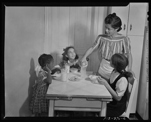 Washington, D.C. Jewal Mazique [i.e. Jewel], worker at the Library of Congress, serving dinner to her three nieces whom she is bringing up and educating