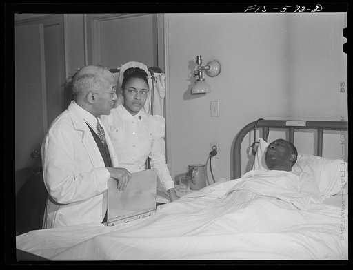 Chicago, Illinois. Provident Hospital. Doctor and a nurse attending a patient in the men's ward