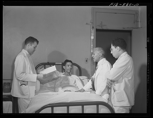 Chicago, Illinois. Provident Hospital. Doctor and interns attending a patient in the men's ward