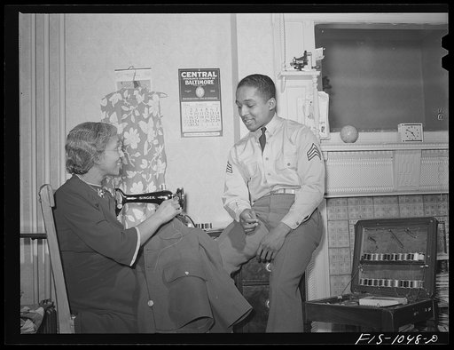 Baltimore, Maryland. Sargeant Franklin Williams, home on leave from Army duty, watching his mother sew a button on his uniform