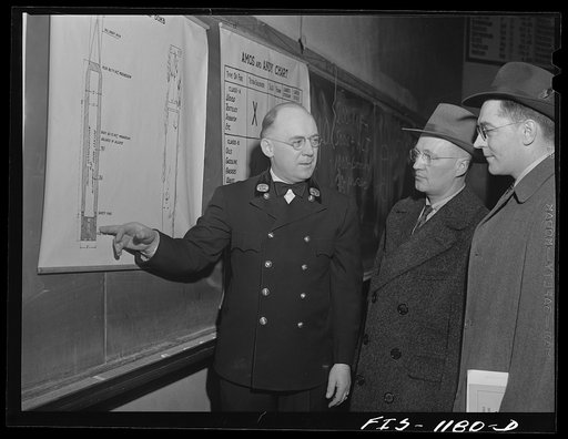 Fire department official in a small Minnesota town instructing Swedish-American civilian defense firespotters with a diagram of an incendiary bomb