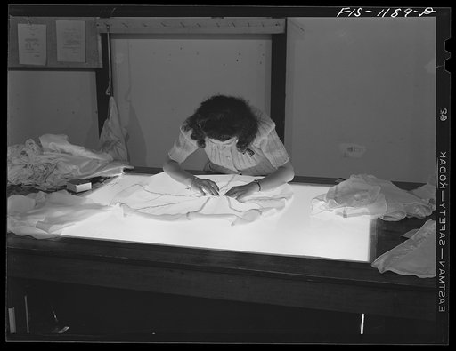 Untitled photo, possibly related to: Mexican girl inspecting the shrouds or briddle of a pilot parachute made at the Pacific Parachute Company. San Diego, California