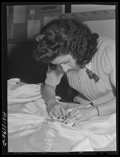 Mexican girl inspecting the shrouds or briddle of a pilot parachute made at the Pacific Parachute Company. San Diego, California