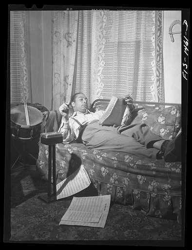 Mr. Oliver Coleman, drummer, looking over some music scores in the study of his apartment on Indiana Avenue. Chicago, Illinois