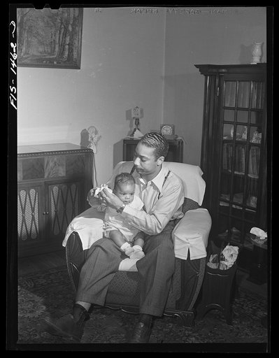Oliver Coleman with his five-month-old son in the living room of his apartment on Indiana Avenue. Chicago, Illinois