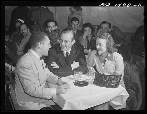 Untitled photo, possibly related to: Between numbers "Red" sits down to chat with friends who have come to the Club DeLisa, Chicago, Illinois. With him are Sam Brooks, also a drummer, but who is now working in an ordnance plant, and Miss Louise Rean who works in an airline office in the city