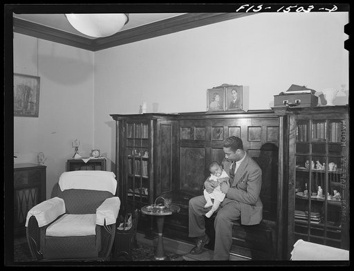 Oliver Coleman with his five-month-old son in the living room of his apartment on Indiana Avenue. Chicago, Illinois