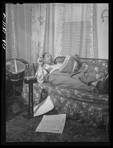 Untitled photo, possibly related to: Mr. Oliver Coleman, drummer, looking over some music scores in the study of his apartment on Indiana Avenue. Chicago, Illinois