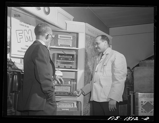 Chicago, Illinois. Mr. William H. Green, owner of a radio and electrical store, waiting on a customer in his shop