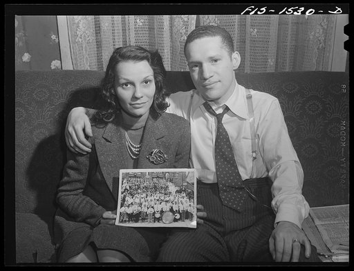 "Red" Sounders [i.e. Saunders] and his wife with an old picture of his graduating class in grammar school. In the front row, exactly in the center, "Red" is standing with a small drum in his hands. Chicago, Illinois
