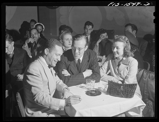 Between numbers "Red" sits down to chat with friends who have come to the Club DeLisa, Chicago, Illinois. With him are Sam Brooks, also a drummer, but who is now working in an ordnance plant, and Miss Louise Rean who works in an airline office in the city