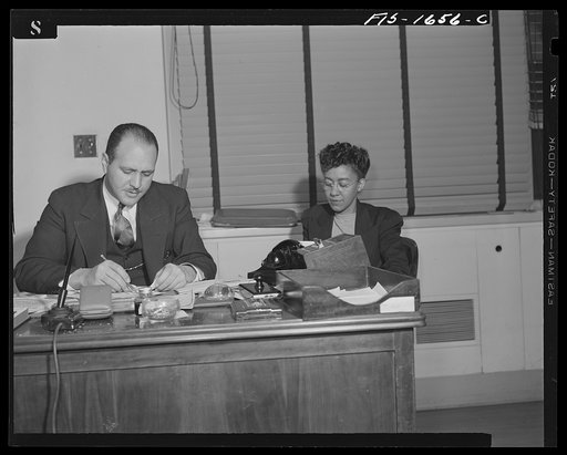 Washington, D.C. Doctor Robert C. Weaver, Chief of the Minority Groups, Bureau of Placement, War Manpower Commission, until February 1944, when he went to Chicago to become codirector of the mayor's interracial committee, set up on racial relations following the Detroit riots. Shown with a secretary