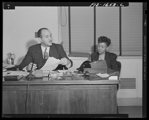 Washington, D.C. Doctor Robert C. Weaver, Chief of the Minority Groups, Bureau of Placement, War Manpower Commission, until February 1944, when he went to Chicago to become codirector of the mayor's interracial committee, set up on racial relations following the Detroit riots. Shown with a secretary