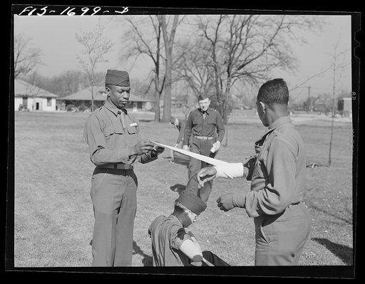 Chaplain Lorenzo Evans removing a bandage from Chaplain Joseph R. Middleton after a first aid class at the U.S. Army chaplain school. Fort Benjamin Harrison, Indiana