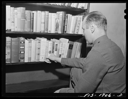 The recreation hall at the chaplain school has a small library of books donated by interested persons in Indianapolis. Here, Chaplain Willard James chooses a book on religion. U.S. Army chaplain school, Fort Benjamin Harrison, Indiana