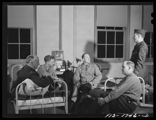 A group of chaplains congregate around the bed of Chaplain (Major) P.S. Hall, Episcopalian, of Upper Darby, Pennsylvania to hear his experiences as chaplain in the last war. U.S. Army chaplain school, Fort Benjamin Harrison, Indiana