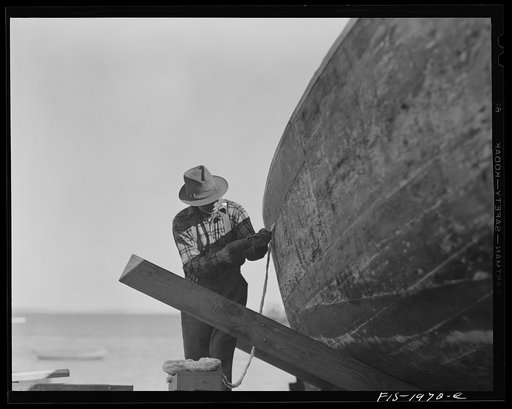 Untitled photo, possibly related to: Provincetown, Massachusetts. Portuguese workmen building a cabin on an open dory