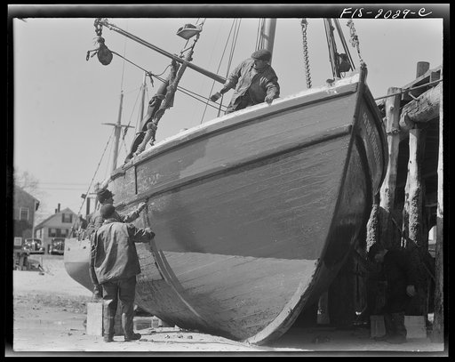 Untitled photo, possibly related to: Provincetown, Massachusetts. The crew of the Frances and Marion, a Portuguese trawler, painting ship on the beach