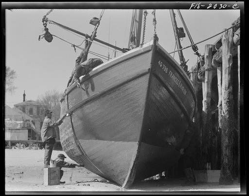 Provincetown, Massachusetts. The crew of the Frances and Marion, a Portuguese trawler, painting ship on the beach