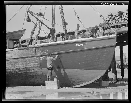 Provincetown, Massachusetts. The crew of the Frances and Marion, a Portuguese trawler, painting ship on the beach