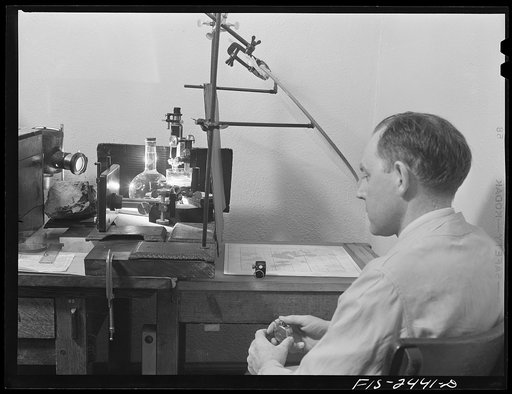 Professor Peterson of the Soils and Agronomy Department with apparatus for making counts of aggregates in a study of soil structure. On the ruled paper on the right appears an image of soil particles magnified 100 times. Iowa State College. Ames, Iowa