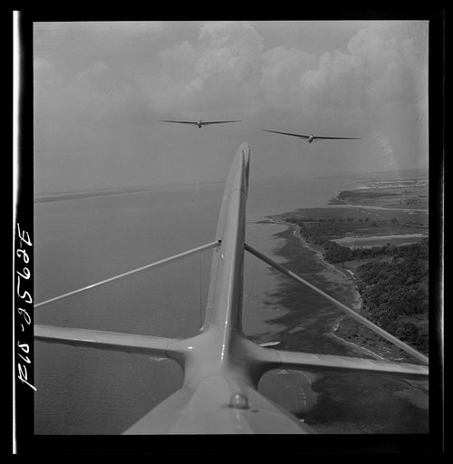 Parris Island, South Carolina. U.S. Marine Corps glider detachment training camp. An aerial "tug boat" tows three gliders high above the field