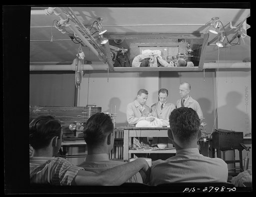 A class in the veterinary school with a rabbit on the operating table. About to operate are: left to right, Robert Pierson, Leon Kanegis, and Dr. E.A. Hewitt. Ames, Iowa