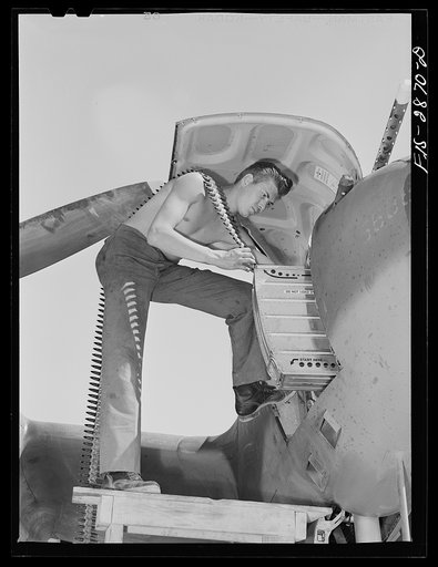 Armorer placing fifty caliber machine gun in pursuit plane at Lake Muroc, California