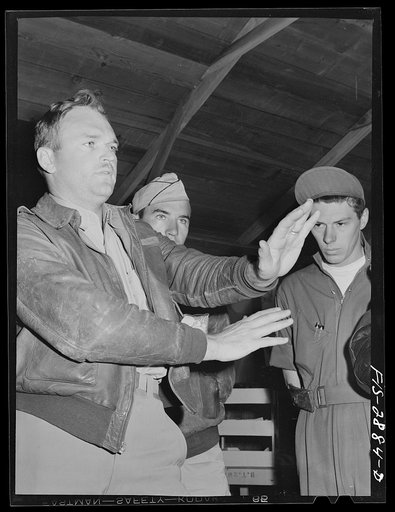 Captain of a squadron of "Flying Sergeants" explains how best to execute a difficult maneuver. Lake Muroc, California