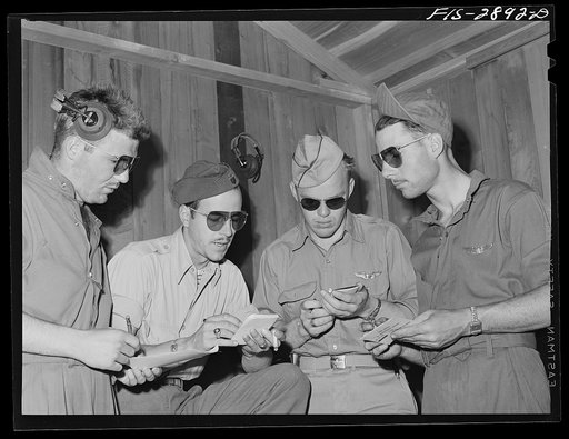 A lieutenant of a "Flying Sergeant" intercepter squadron (second from the left) charts the manner of the formations. Lake Muroc, California