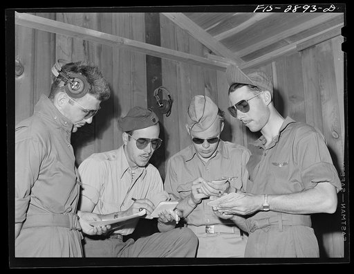 A lieutenant of a "Flying Sergeant" intercepter squadron (second from the left) charts the manner of the formations. Lake Muroc, California