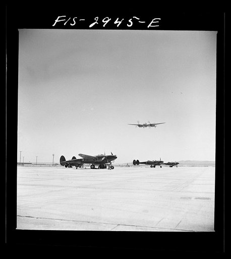 "Buzzing" the field. Member of interceptor squadron swoops low over parked airplanes to stimulate a strafing attack on an airport. Lake Muroc, California