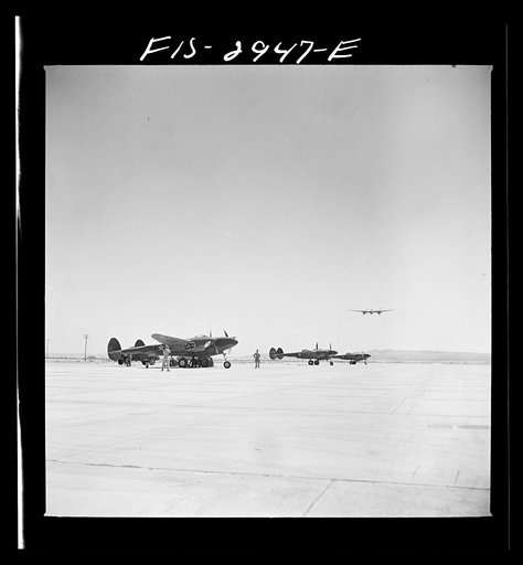 Untitled photo, possibly related to: "Buzzing" the field. Member of interceptor squadron swoops low over parked airplanes to stimulate a strafing attack on an airport. Lake Muroc, California
