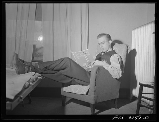 Jim Tillma reading a technical journal in his rooming house. University of Nebraska, Lincoln