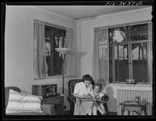Untitled photo, possibly related to: Greenbelt, Maryland. Federal housing project. Mrs. Leslie Atkins reading to her daughter Ann in the living room of her home. It is the corner house of a row of flat-roofed houses. All living rooms have cross ventilation