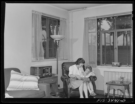 Greenbelt, Maryland. Federal housing project. Mrs. Leslie Atkins reading to her daughter Ann in the living room of her home. It is the corner house of a row of flat-roofed houses. All living rooms have cross ventilation