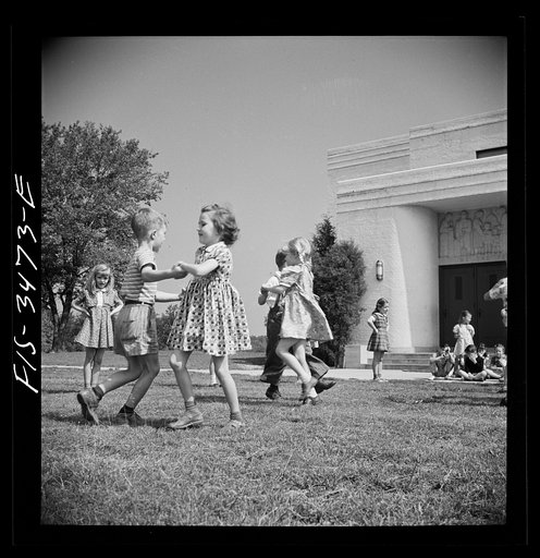 Untitled photo, possibly related to: Greenbelt, Maryland. Federal housing project. Kindergarten children practice their May Day dances on the grass in front of the school