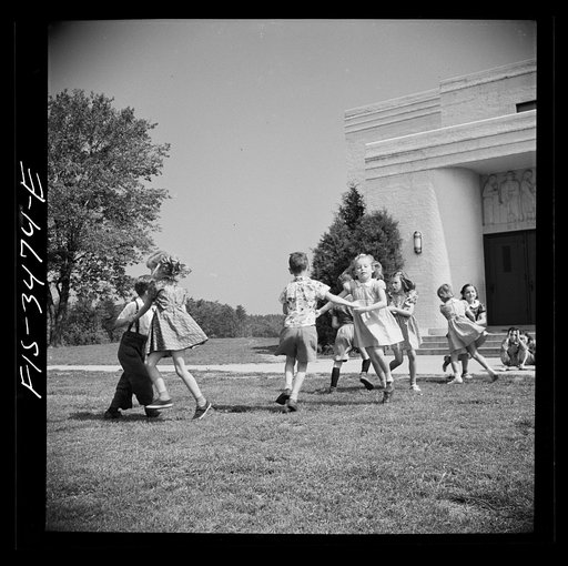 Greenbelt, Maryland. Federal housing project. Kindergarten children practice their May Day dances on the grass in front of the school