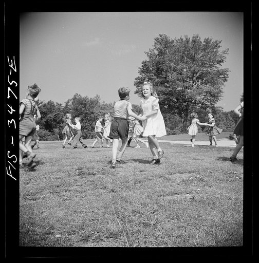 Greenbelt, Maryland. Federal housing project. Kindergarten children practice their May Day dances on the grass in front of the school