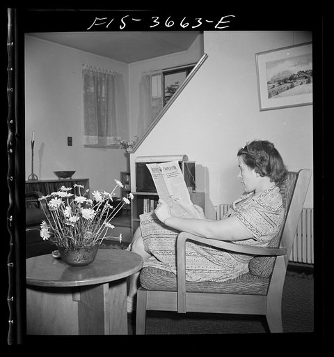 Untitled photo, possibly related to: Greenbelt, Maryland. Mrs. Hoover reading a copy of the Greenbelt Cooperator. The chair and table are special skills furniture, designed especially for the project