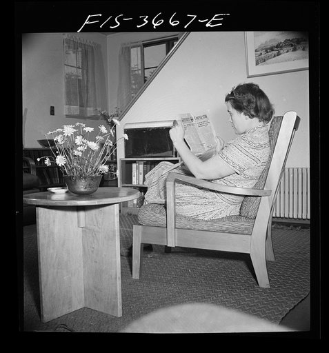 Greenbelt, Maryland. Mrs. Hoover reading a copy of the Greenbelt Cooperator. The chair and table are special skills furniture, designed especially for the project