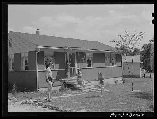 Untitled photo, possibly related to: Sheffield, Alabama (Tennessee Valley Authority (TVA)). Kenneth Hall gives daughter Peggy a shower with garden hose in front of their TVA defense home
