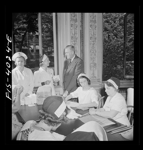 Untitled photo, possibly related to: Washington D.C. Mr. Lund, who is the head of the District Red Cross, dropped in at the District chapter house where a Norwegian unit of the Red Cross was wrapping bandages