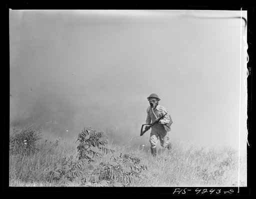 Fort Riley, Kansas. A soldier of a rifle platoon of a calvalry unit advancing through a smokescreen during a sham battle