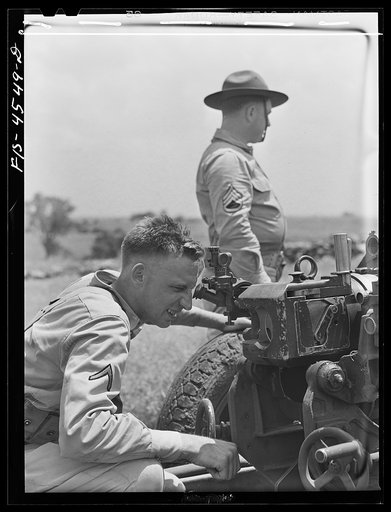 Untitled photo, possibly related to: Fort Riley, Kansas. Sighting a howitzer 75 mm gun during artillery practice